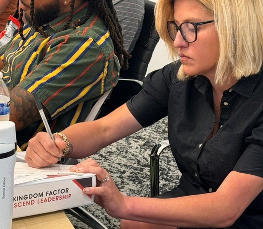 An Ascend Leadership member receiving her personalized Kingdom Factor Ascend Leadership binder